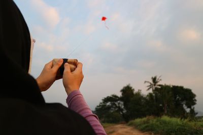 Midsection of woman holding umbrella against sky during sunset