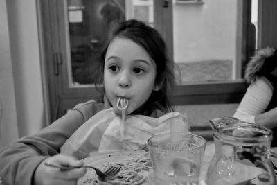 Portrait of cute girl sitting on table at home