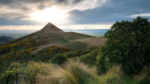 Sun setting down behind an unusually shaped mountain,sunset in port hills, christchurch, new zealand