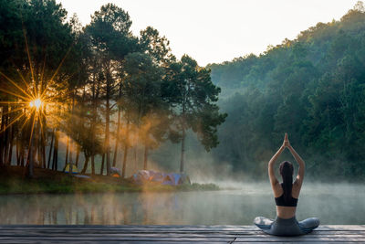 Woman standing by lake against trees