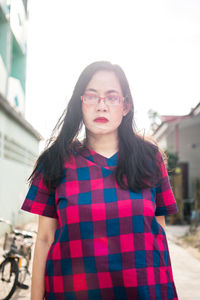 Portrait of beautiful young woman standing against wall