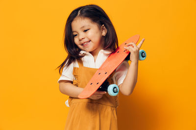 Portrait of young woman holding gift against yellow background