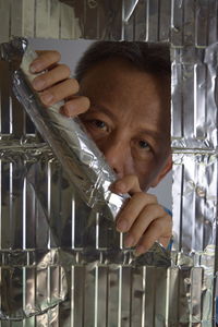 Close-up portrait of man looking through foil paper