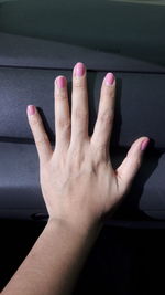 Cropped hand of woman with painted fingernails at home