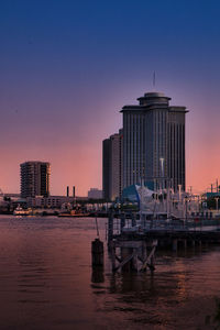 Buildings by river against clear sky