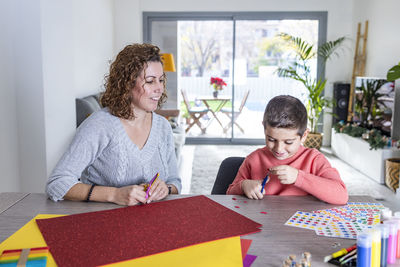 Mother and son making crafts at home with cardstocks and stickers