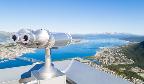 Coin-operated binoculars against sea during sunny day