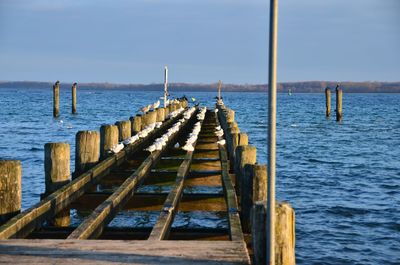 Wooden pier over sea against sky