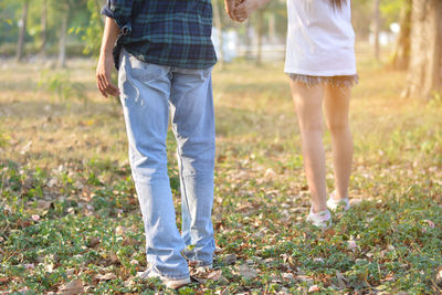 Low section of couple standing on field