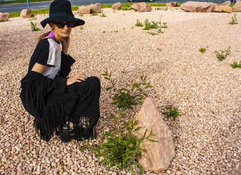 Side view of woman sitting on sidewalk