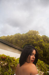 Portrait of woman looking at trees against sky