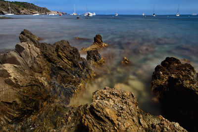 Close-up of sea by rocks against sky