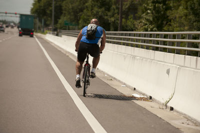 Rear view of man riding bicycle on road