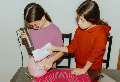 Two beautiful caucasian girls are baking cookies.