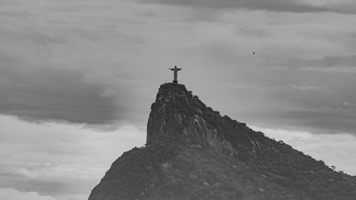 Low angle view of cross on rock against sky