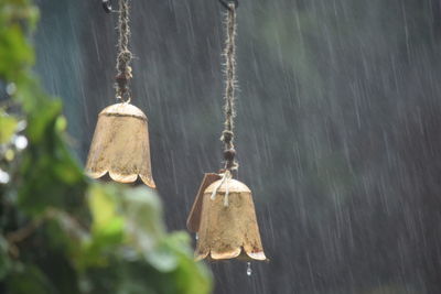 Metallic bells hanging outdoors during monsoon