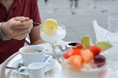 Midsection of man having drink at sidewalk cafe