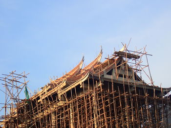 Low angle view of crane by building against clear sky