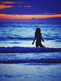 Silhouette woman on beach against sky during sunset