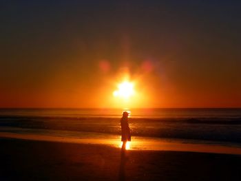 Silhouette woman on beach against sky during sunset