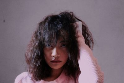 Close-up portrait of a young woman against gray background