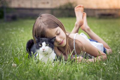 Little girl cuddling with cat on a meadow