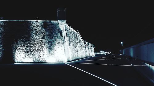 Illuminated road against clear sky at night