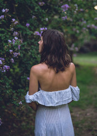 Rear view of woman standing against trees