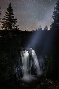 Scenic view of waterfall against sky at night