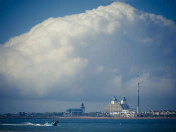 View of buildings by sea against cloudy sky