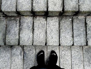 Low section of man standing in front of footpath