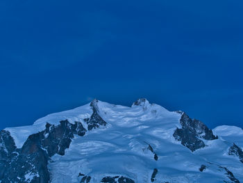 Scenic view of snowcapped mountains against clear blue sky