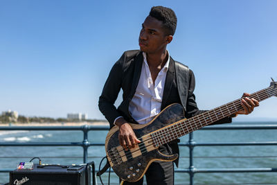 Man playing guitar against sky