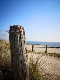 Wooden fence on beach against clear sky