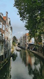 Canal in city against sky