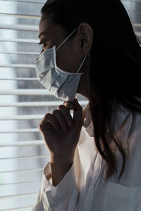 Close-up portrait of a young woman holding window