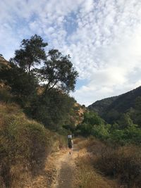 Rear view of man walking on mountain against sky