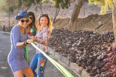 Happy friends pulling rope while playing tug-of-war on road