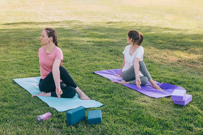 Two young women in the park doing yoga in the morning. exercising outdoors, healthy lifestyle