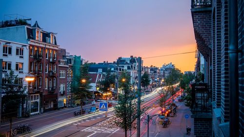 City street and buildings against sky at dusk