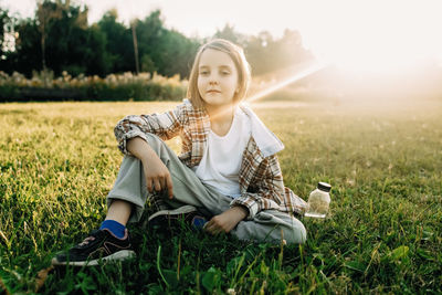 A girl sits in a park on the grass, outdoor recreation concept
