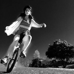 Low angle view of woman riding unicycle on field