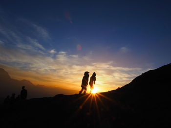 Silhouette people standing against sky during sunset
