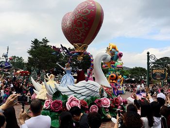 Crowd at balloons against sky