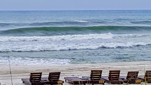 Chairs on beach against sky