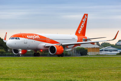 Airplane flying over grassy field against sky