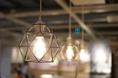 Close-up of illuminated light bulb hanging from ceiling