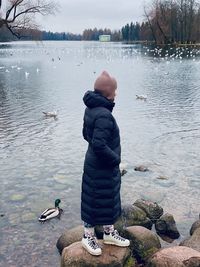Rear view of man standing in lake during winter
