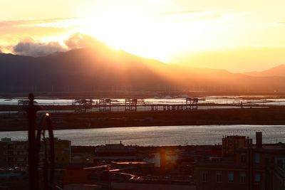 High angle view of sea and cityscape against sky during sunset