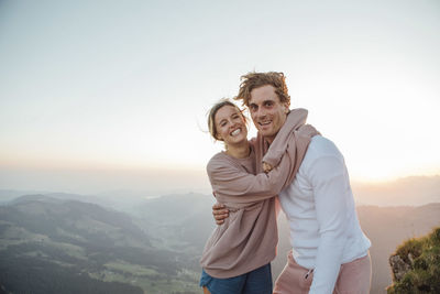 Switzerland, grosser mythen, portrait of happy young couple hugging in mountainscape at sunrise
